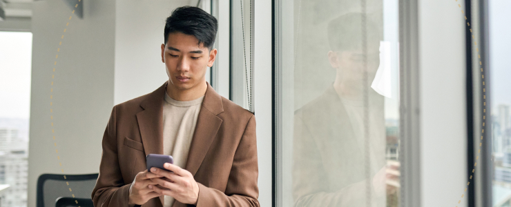Un homme en costume est concentré sur son téléphone, semblant être en pleine conversation ou en train de consulter ses messages.
