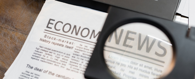 Primer plano de un artículo sobre noticias económicas bajo una lupa, en el que destaca el título «NOTICIAS ECONÓMICAS» y su relación con la estrategia de trading.