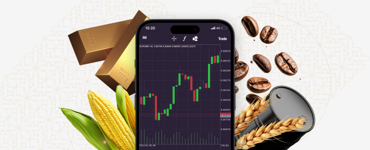 A smartphone displays a candlestick chart, surrounded by gold bars, corn, wheat, coffee beans, and an oil barrel, representing various commodities.