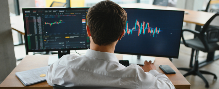 A trader man seated at a desk, analyzing trading data on two monitors showing different financial graphs and metrics, metatrader 4 analysis platform