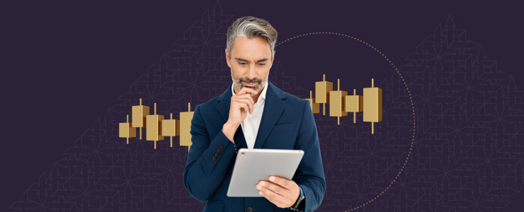 A suited trader man holds a tablet, reviewing trading indices and market analysis for gold investments.